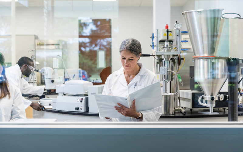 lab researcher reading binder - CREDIT_iStock-1646508449