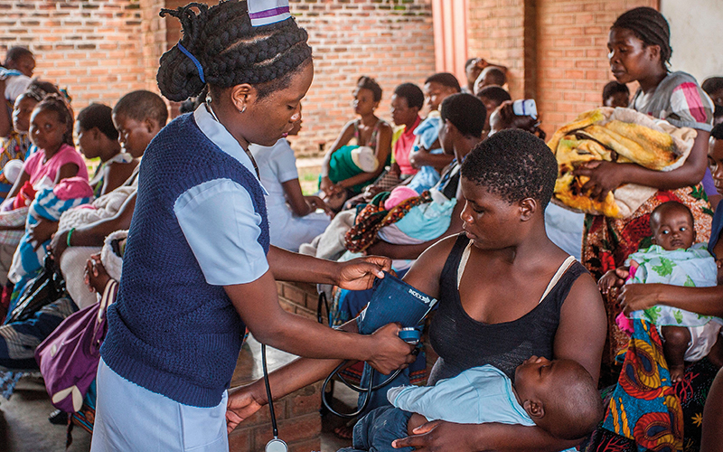 A nurse takes the blood pressures of a woman as she waits with an infant at Ndirande Health Centre in Blantyre on February 21, 2018 - Image credit - Getty-922184246